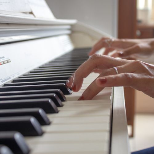 Woman's hand playing on a white piano