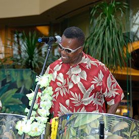 Caribbean steel drum player with a red and white shirt on playing outside at party