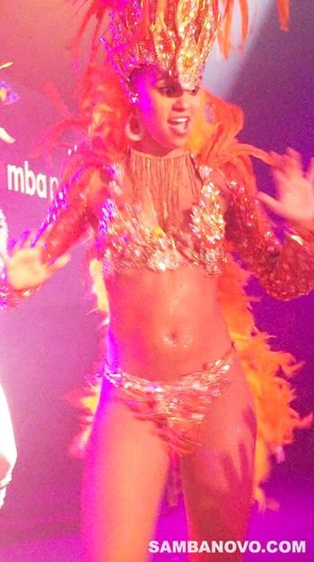 Gorgeous Brazilian dancer for hire live on stage in a bright orange costume giving an extravagant and exciting performance
