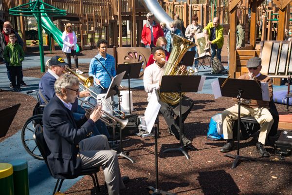 A performance at a playground by an ensemble of Black and white Binghamton Philharmonic brass musicians