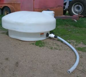 Photo of food grade plastic tank with hose on the ground