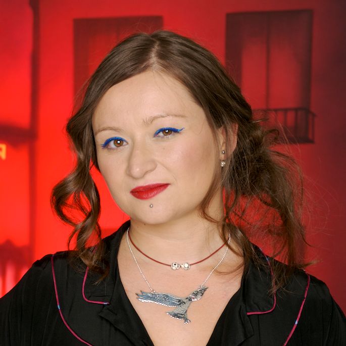Photo Of Eliza Carthy looking straight ahead with red lips & red background